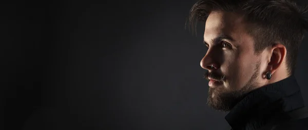 Guapo chico brutal con barba sobre fondo oscuro —  Fotos de Stock