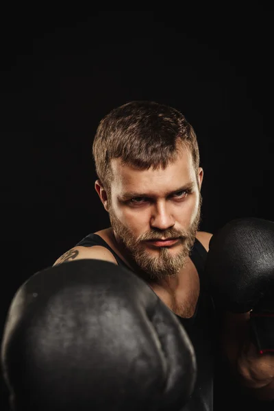 Sportovní vousatý boxer s rukavicemi na tmavém pozadí — Stock fotografie