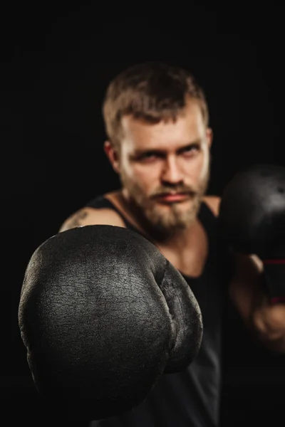 Sportovní vousatý boxer s rukavicemi na tmavém pozadí — Stock fotografie