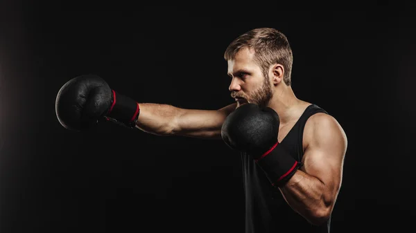 Sportovní vousatý boxer s rukavicemi na tmavém pozadí — Stock fotografie