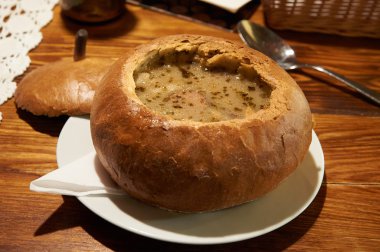 Polish traditional soup Zurek in bread, selective focus