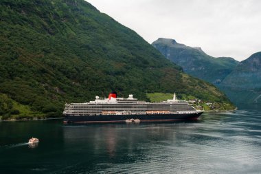 Geiranger fiyordunun sonunda yolcu gemisi yanaştı, yolcuları karaya çıkmaya hazırlıyor.