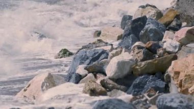 Okyanus dalgaları güneşli bir günde gün batımında kayalara çarpar.