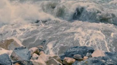 Okyanus dalgaları güneşli bir günde gün batımında kayalara çarpar.