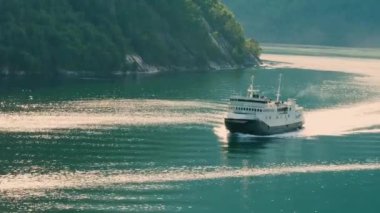 Yolcu gemisi yazın Norveç fiyortlarından geçiyor, gezginler güverteden manzarayı seyrediyor.