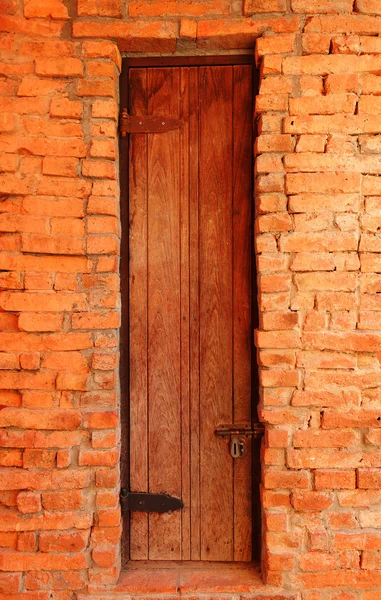 Porta de madeira velha na parede de tijolo — Fotografia de Stock