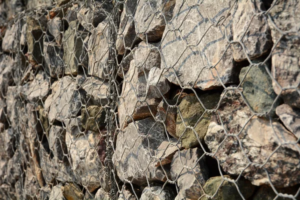 A volcanic stone and steel net fence texture background — Stock Photo, Image