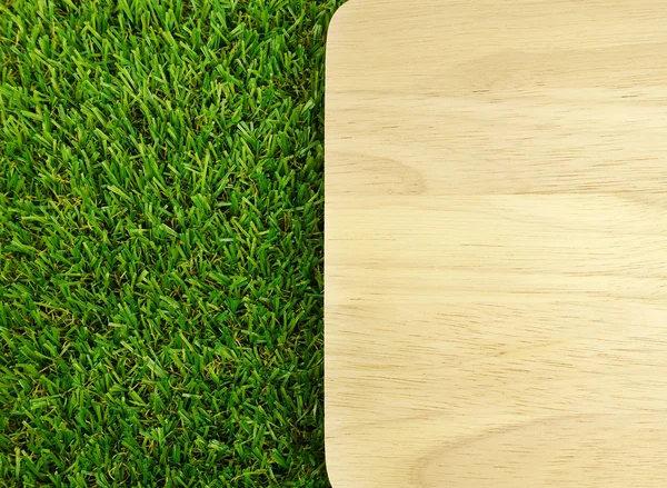 Wood board on green grass — Stock Photo, Image