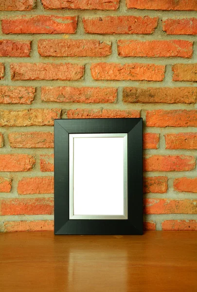 Back picture frame on the old brick wall and the wooden floor — Stock Photo, Image