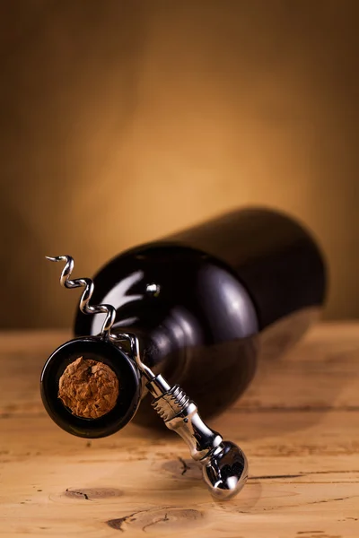 Fles wijn en kurkentrekker op tafel — Stockfoto