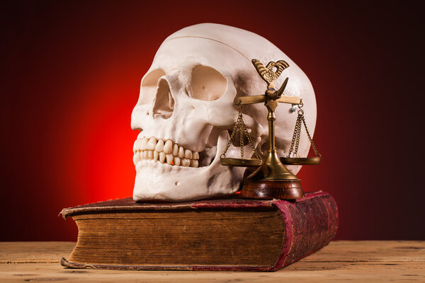 Human scull  scales of justice and old book