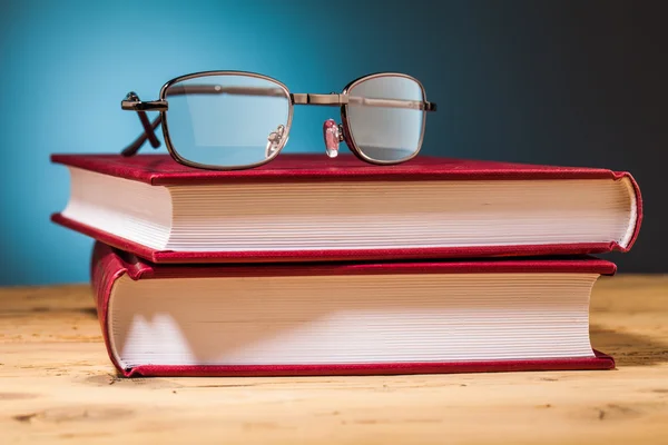 Böcker och glasögon på träbord — Stockfoto