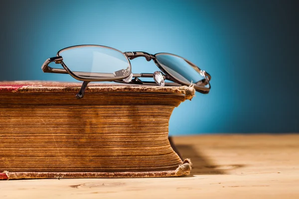 Gammal bok och glasögon på träbord — Stockfoto