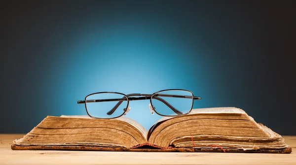 Livro e óculos em mesa de madeira — Fotografia de Stock