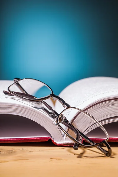 Livro e óculos em mesa de madeira — Fotografia de Stock