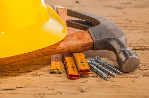Capacete amarelo, martelo e ferramentas de montagem — Fotografia de Stock