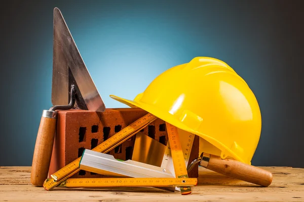 Yellow helmet, brick and builder tools — Stock Photo, Image