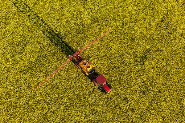 Vista aérea dos campos de colheita de colza amarela com trator — Fotografia de Stock