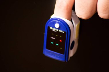 Nabız oksimetresi ve hasta eli. Nabız oksimetresi taşınabilir dijital aygıt kişinin oksijen doygunluğunu ölçmek için.