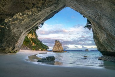 Güneş doğarken Katedral Koyu 'ndaki mağaradan manzara, Yeni Zelanda' da Coromandel.