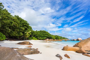 Turkuaz su, granit kayalar ve tropik sahildeki beyaz kumda palmiye ağaçları Seyşeller 'deki Anse Lazio' da.