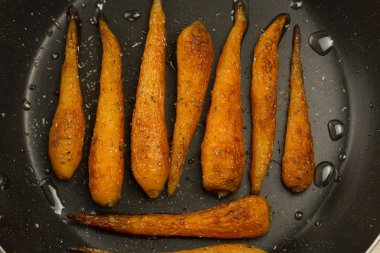 Bütün kavrulmuş havuç ile bir tavada baharat. Sağlıklı yemek