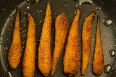 Bütün kavrulmuş havuç ile bir tavada baharat. Sağlıklı yemek