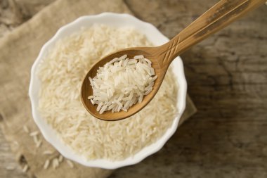 long grain rice in a wooden spoon on a background plate. Healthy eating, diet, vegetarianism.