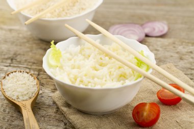 White plate of cooked long-grain rice on wooden background. Healthy eating, diet, vegetarianism.