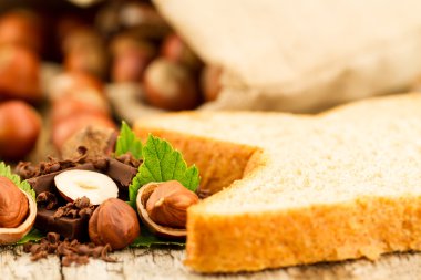 hazelnut with chocolate, toast and green leaves on old wooden background