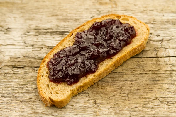 Morceau de pain de seigle avec confiture sur fond en bois — Photo