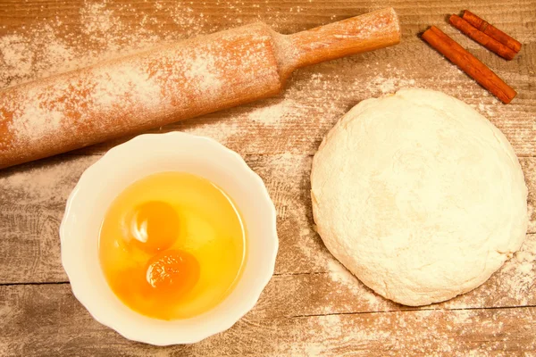 Hornear en casa. Masa fresca para repostería, canela palo, harina derramada, huevos rotos en una tabla de cortar — Foto de Stock