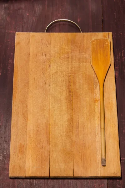 Řezací deska a kuchyňské stěrky na dřevěné pozadí — Stock fotografie
