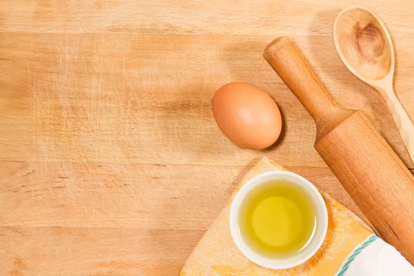 Hornear en casa. Rodillo de cocina, cuchara, toalla, aceite de oliva, huevo de pollo en la tabla de cortar vintage — Foto de Stock