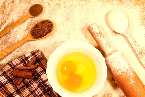 Hornear en casa. Rodillo de cocina, harina de cuchara, huevos rotos, aceite de girasol, toalla en una tabla de cortar — Foto de Stock