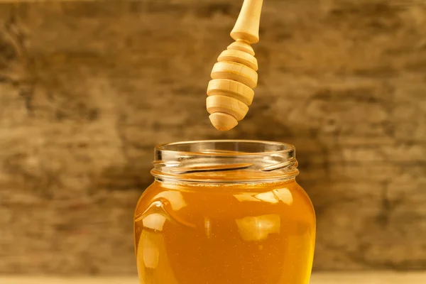 Glas Honig mit Nieselregen auf Holzgrund — Stockfoto