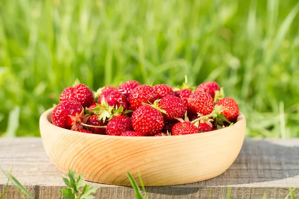 Fresh ripe strawberries in a wooden bowl on a green meadow — Stock Photo, Image