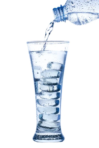 Pouring water in an elegant tall glass with ice and water drops on white background — Stock Photo, Image