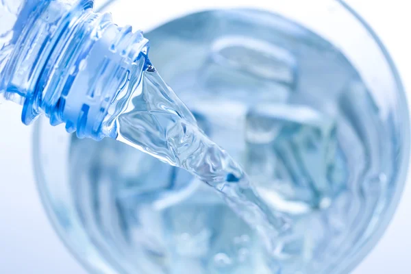 Pouring water in an elegant glass with ice and water drops. Macro — Stock Photo, Image