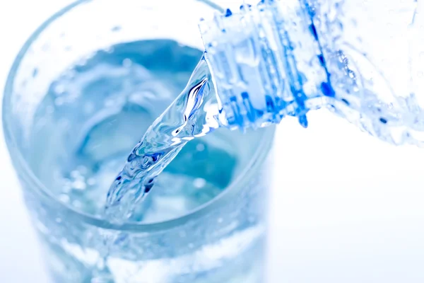 Наливая воду в элегантный стакан со льдом и каплями воды. Макро — стоковое фото