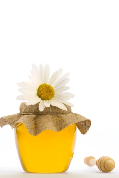 Botol kaca madu segar dengan gerimis dan bunga terisolasi pada latar belakang putih — Stok Foto