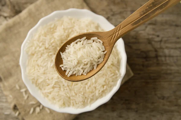 Long grain rice in a wooden spoon on a background plate. Healthy eating, diet, vegetarianism. — Stock Photo, Image