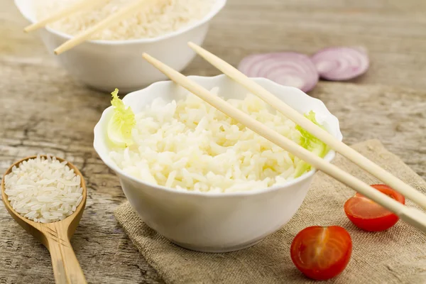 Weißer Teller mit gekochtem Langkornreis auf Holzgrund. gesunde Ernährung, Ernährung, Vegetarismus. — Stockfoto