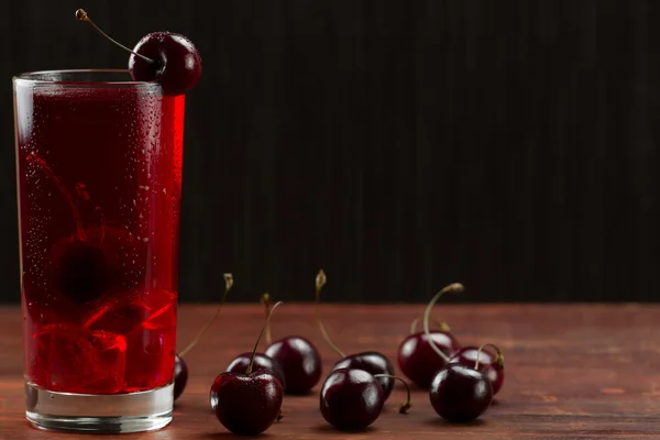 Wiśnia sok z dojrzałymi jagodami na drewnianym tle. Zdrowa dieta — Zdjęcie stockowe