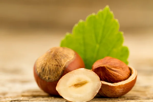 Avellanas con hojas sobre fondo de madera vieja. Comida vegetariana saludable —  Fotos de Stock