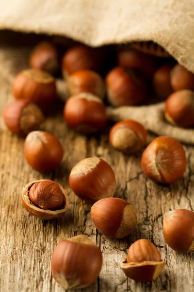 Avellanas dispersas fuera de la bolsa sobre fondo de madera vieja. Comida vegetariana saludable —  Fotos de Stock