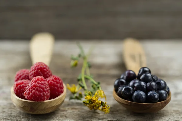 Lamponi e mirtilli in cucchiai su fondo di legno. Note di alimentazione e dieta — Foto Stock