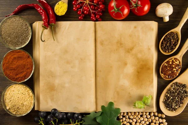 Open old vintage book with spices on wooden background. Healthy vegetarian food. Recipe, menu, mock up, cooking. Stock Image