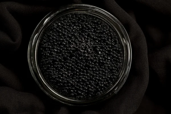 Black Beluga caviar in glass jar on wooden background Stockfoto