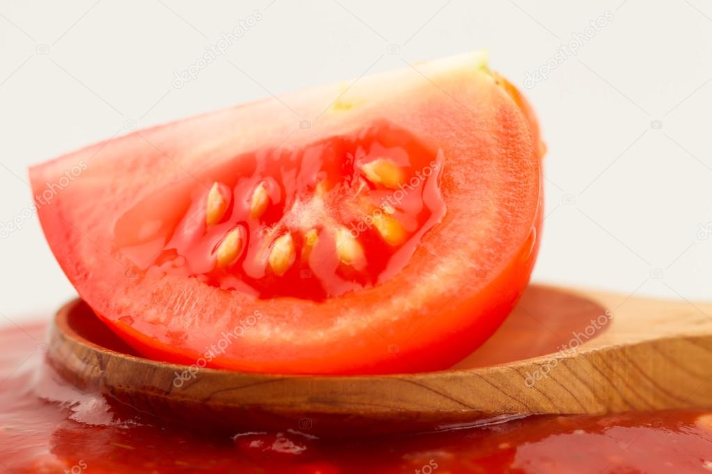 Tomato ketchup in a wooden spoon on a white background. Home made, healthy vegetarian food